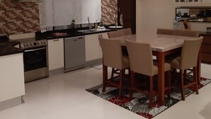 A modern kitchen with a dining area, featuring a central island, built-in oven, and a chandelier. - Luxurious family  villa with fully furnished (Hidd)