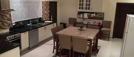 Een magnetron, kookgerei, borden en bestek, eettafels