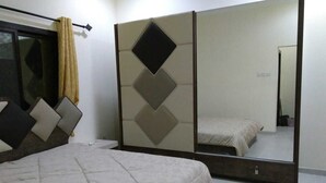 A bedroom with a bed, a large mirror, and a wardrobe. - Luxurious family  villa with fully furnished (Hidd)