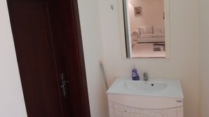 A bathroom with a white sink, a mirror, and a door. - Luxurious family  villa with fully furnished (Hidd)
