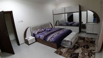 A bedroom with a bed, a nightstand, a dresser, a mirror, and a patterned rug.