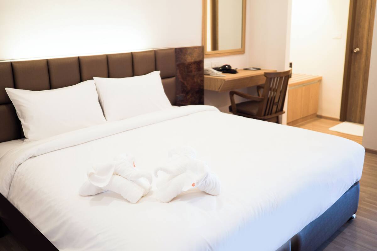 Une chambre d’hôtel avec un lit, un bureau, une chaise et un miroir.