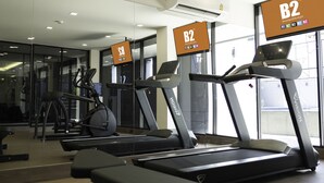 Une salle de sport équipée de plusieurs tapis de course, de vélos d’appartement et d’un appareil d’aviron.
