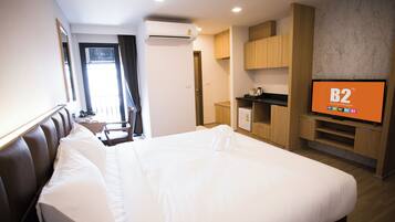 A hotel room with a large bed, a TV displaying 'B2 Boutique Budget', a desk, and a wardrobe.