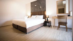 Une chambre d’hôtel moderne, dotée d’un grand lit, de tables de chevet, d’un bureau et d’une chaise.