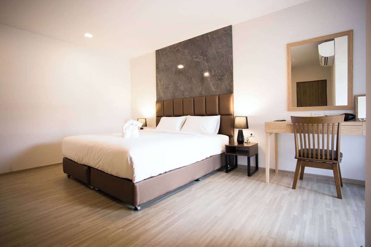 Une chambre d’hôtel moderne, dotée d’un grand lit, de tables de chevet, d’un bureau et d’une chaise.