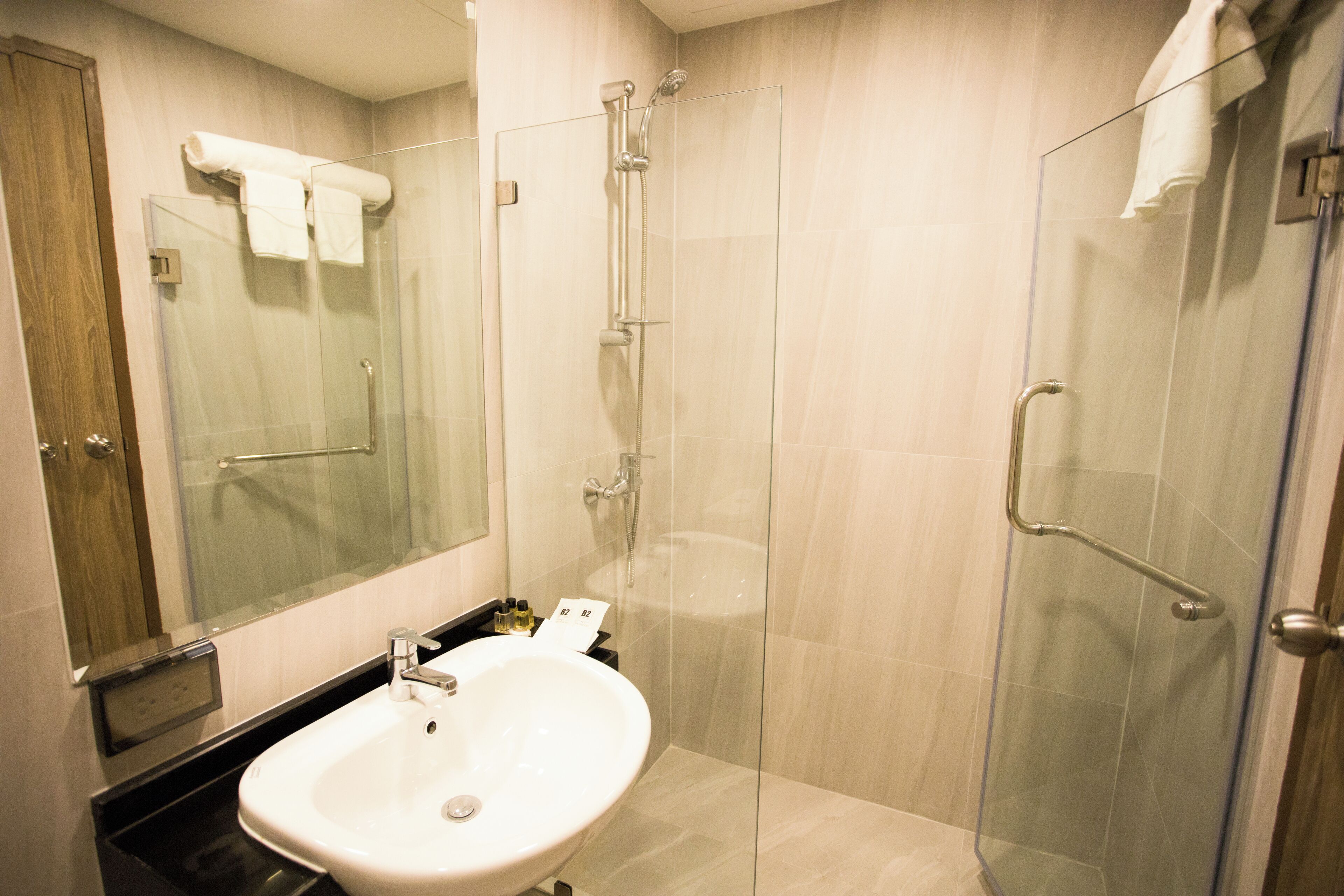Un baño moderno con cabina de ducha de vidrio, un lavamanos blanco y un espejo grande.