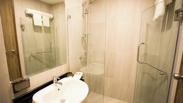 Un baño moderno con cabina de ducha de vidrio, un lavamanos blanco y un espejo grande.