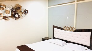 Una cama bien tendida con un cabecero capitonado, una manta marrón y un adorno en la pared.