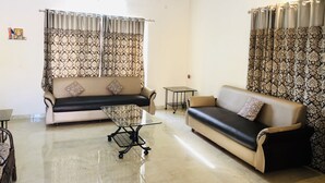 Una sala de estar con dos sofás, una mesa de centro y cortinas estampadas.