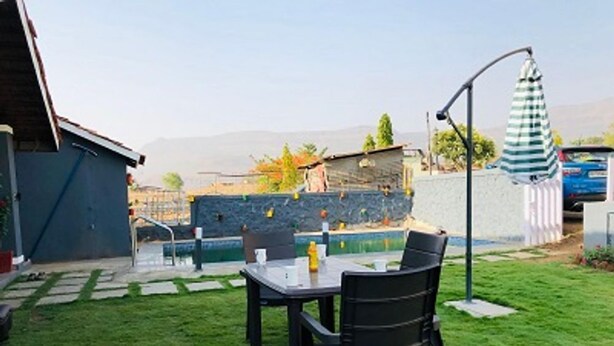 Un patio trasero con una mesa y sillas, una piscina pequeña y un muro de piedra.
