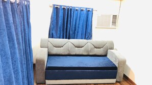 Una habitación con sofá, cortinas y radiador.