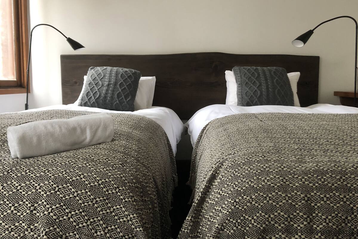 A double bed with a dark headboard, two pillows, and a patterned bedspread.
