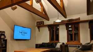 En hyggelig stue med et træbord, en lædersofa og et fjernsyn, der viser 'THE JOINT Hokka'.