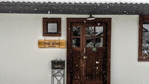 En bygning med et sneklædt tag og en trædør. Et skilt over døren siger "THE JOINT".