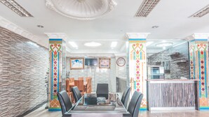 A modern dining area with a glass-top table, black chairs, and a decorative column with a colorful pattern. - Super OYO 1640 Fallinda Hotel (Cibinong)
