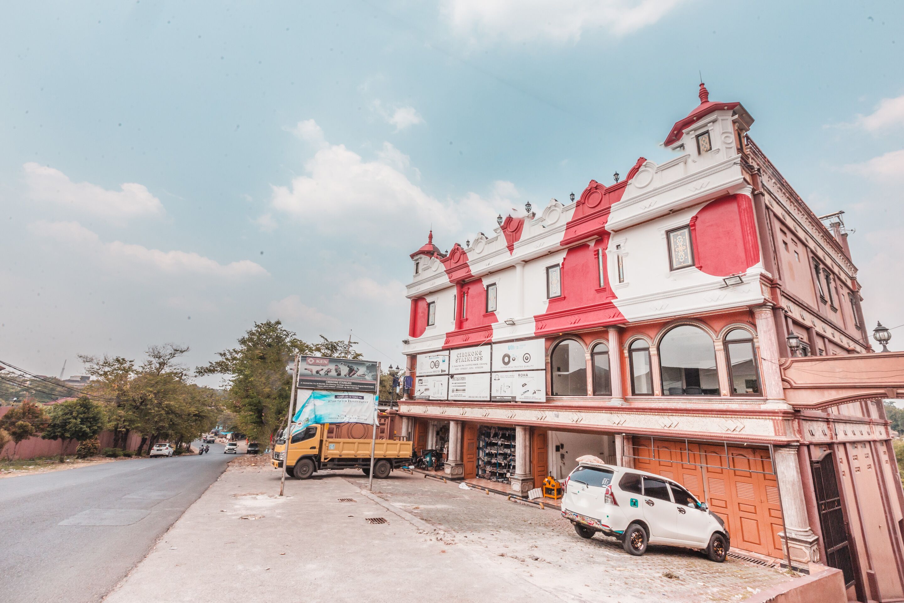 A building with a red and white facade, a storefront, and a parked vehicle.