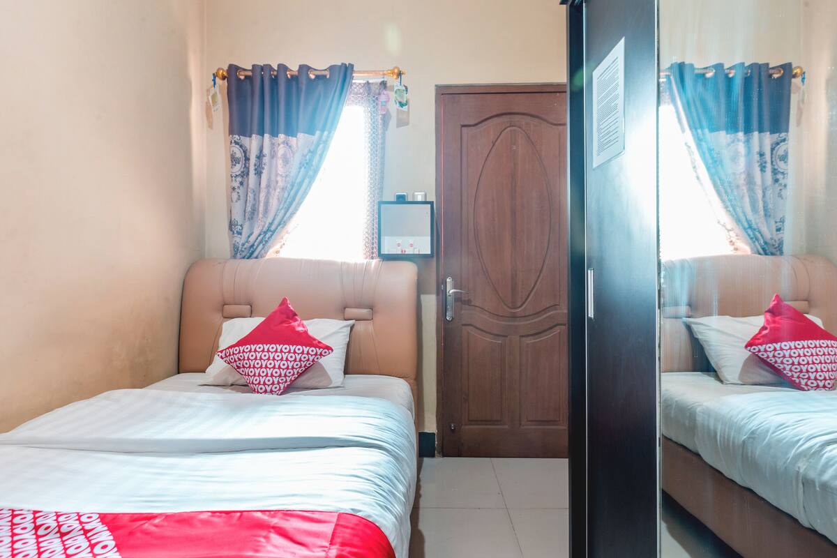 Une chambre avec deux lits, une porte en bois et une fenêtre avec des rideaux.