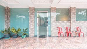A reception area with a tiled floor, potted plants, and red chairs. - Super OYO 1640 Fallinda Hotel (Cibinong)