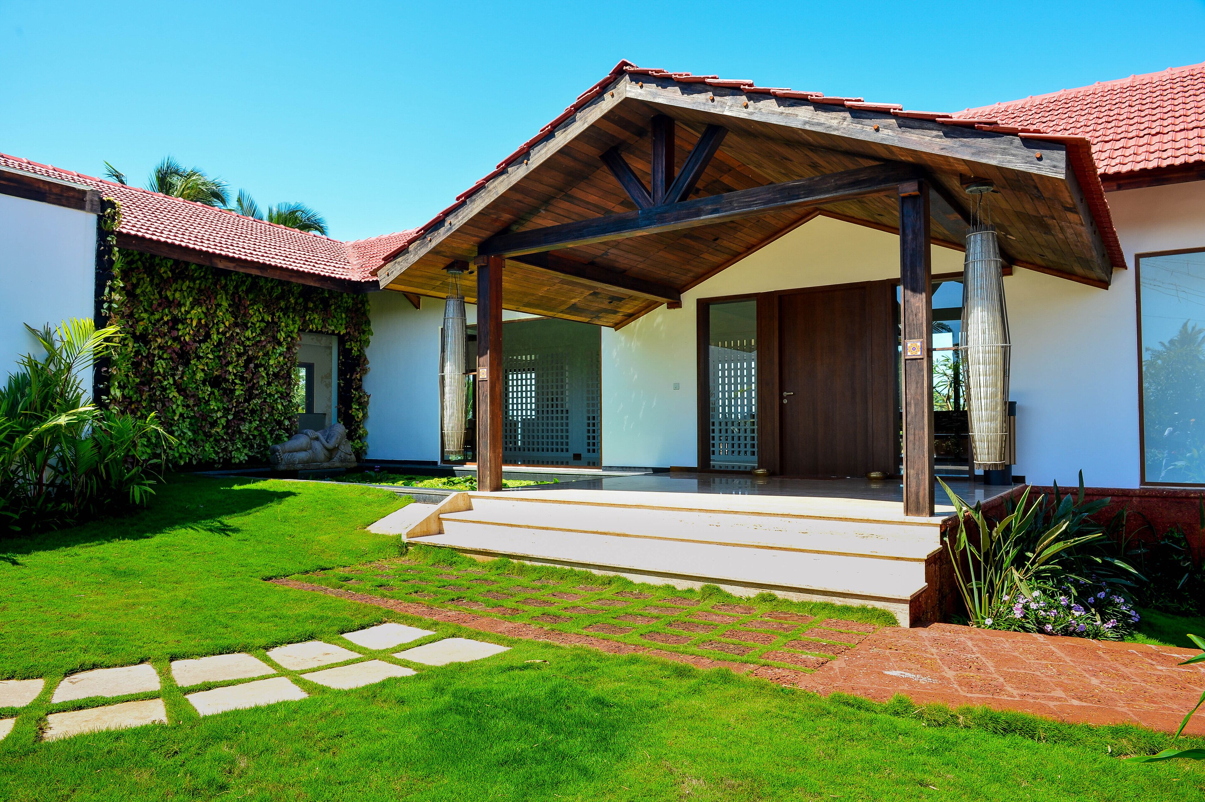 A modern house with a covered porch, a well-maintained lawn, and a brick pathway leading to the entrance.