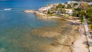 A coastal property with clear waters, a sandy beach, and a view of the sea.