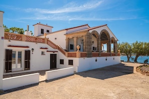 A coastal property with a white facade, a covered patio, and a view of the sea. - Villa Es Clot sea view 8 people BBQ (Alcúdia)