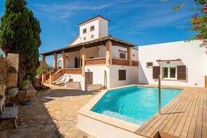 A two-story building with a swimming pool, stone flooring, and a wooden deck.