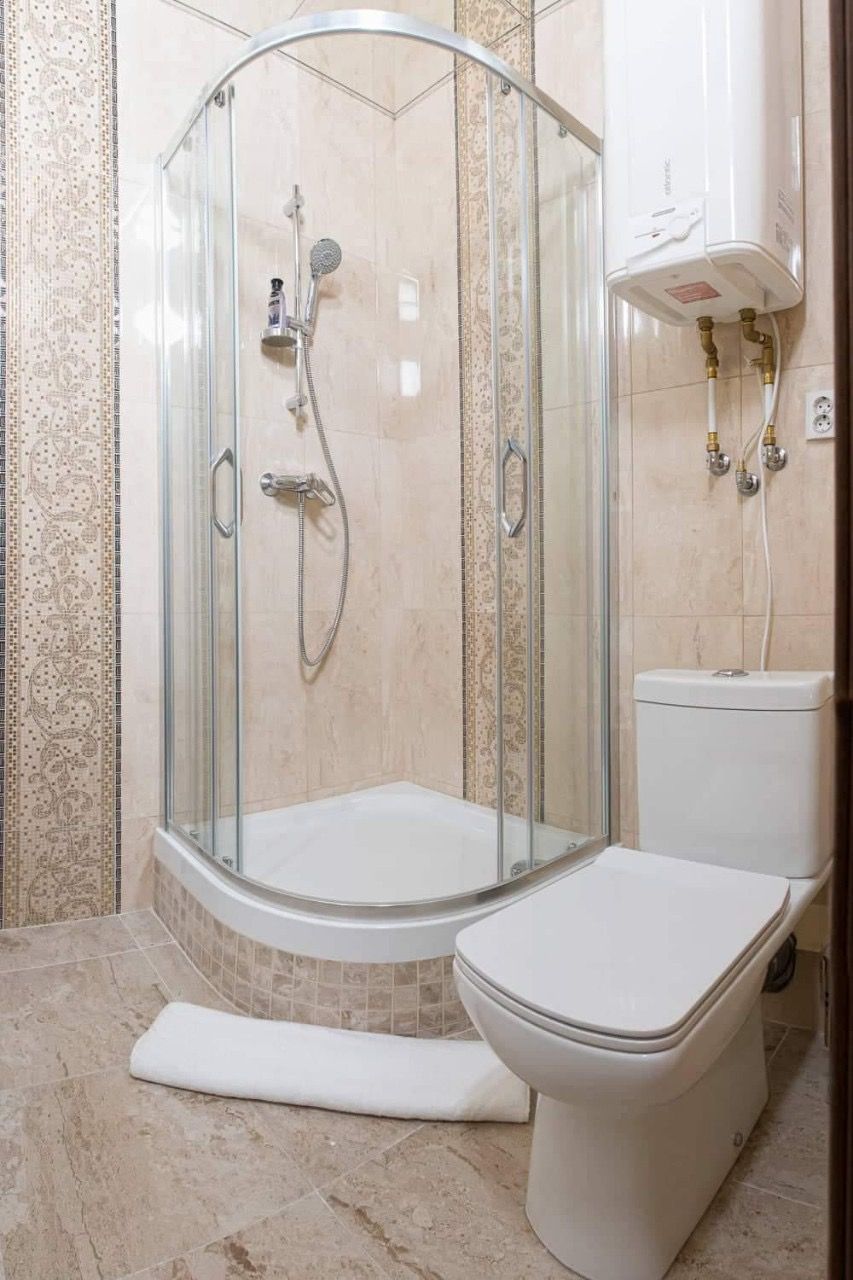 A glass-enclosed shower stall with a toilet and bidet to the right.