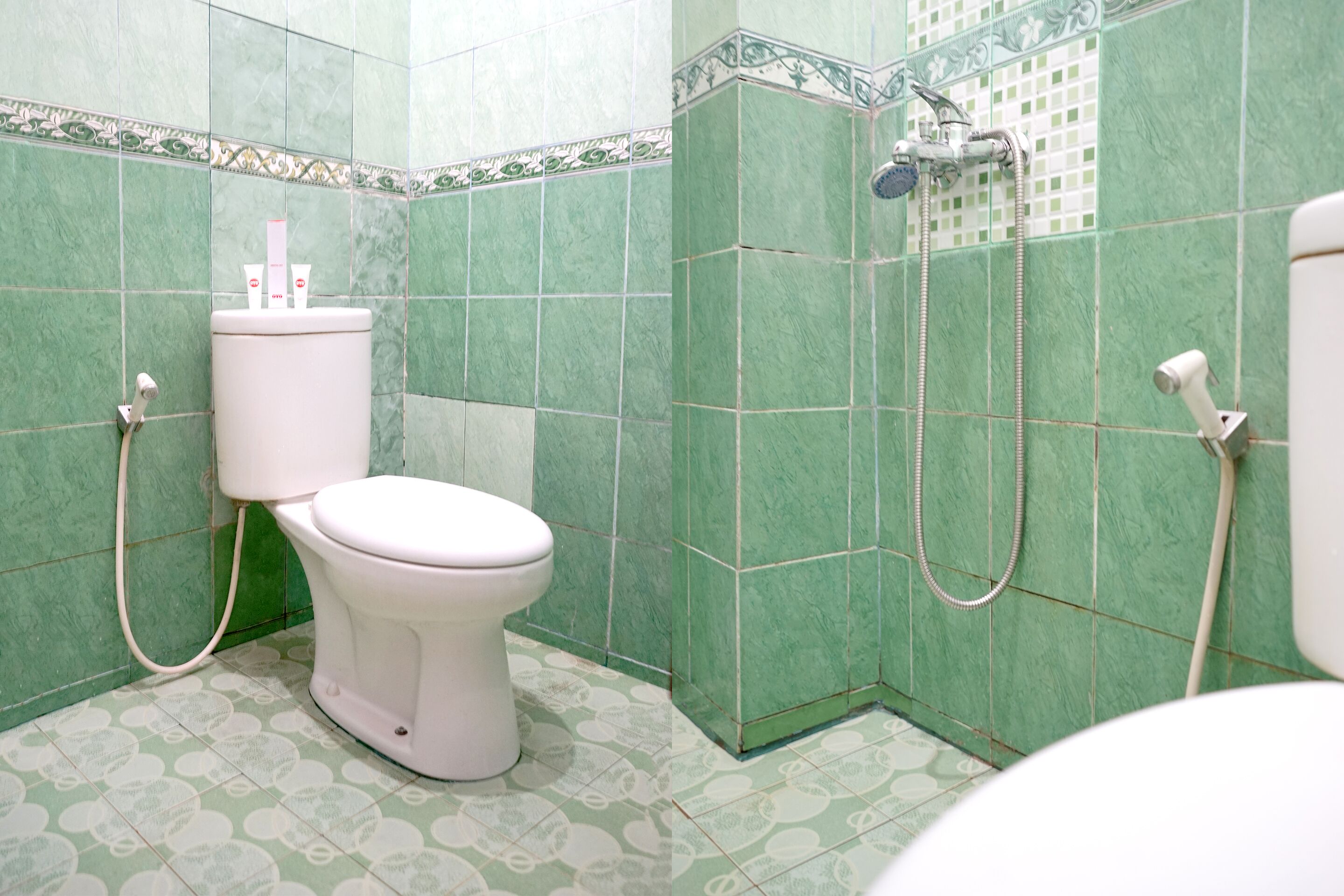 A bathroom with green tiled walls, a toilet, and a shower area.