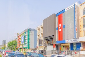A multi-story building with a prominent red vertical sign and a blue horizontal sign. - OYO 1850 The Trend (Jakarta)