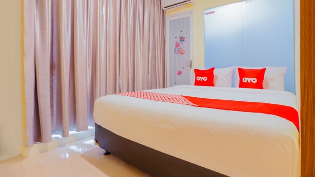 A hotel room with a large bed, a wardrobe, and a window with curtains. - OYO 1850 The Trend (Jakarta)