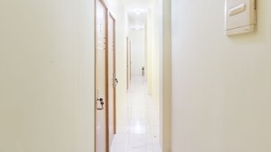 A hallway with wooden doors and a wall-mounted thermostat. - OYO 1850 The Trend (Jakarta)