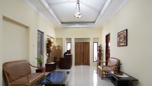 A spacious living area with a sofa, coffee table, and chairs. There is a wooden cabinet and a decorative vase. - Hotel O Bromo Hill (Sukapura)