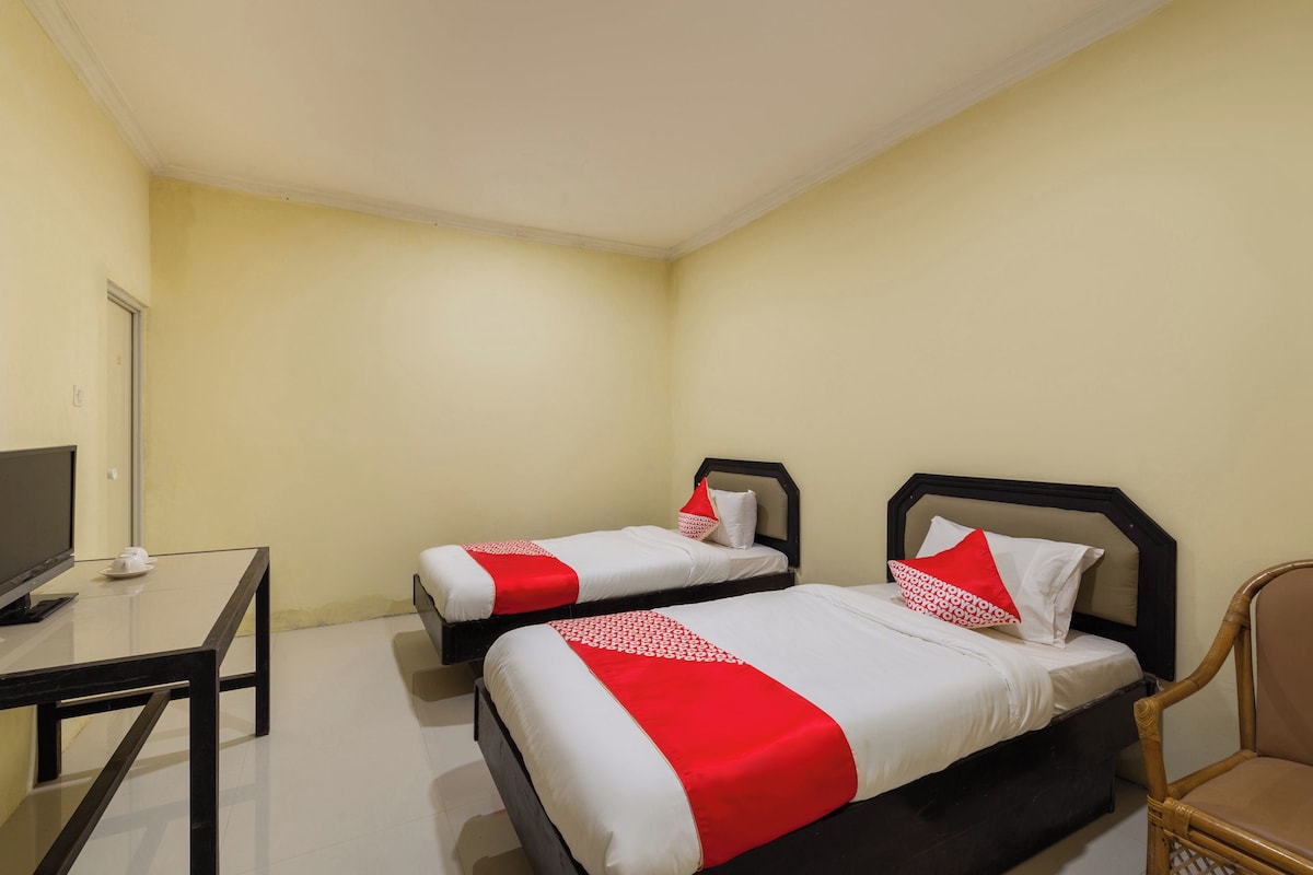 Une chambre d’hôtel avec deux lits, un bureau, une chaise et un téléviseur.