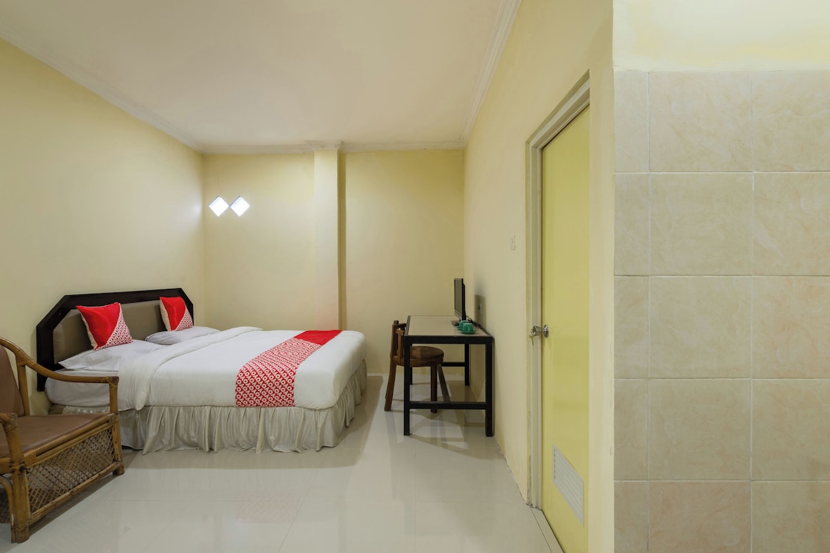 Une chambre d’hôtel avec un lit, un bureau, une chaise et une porte.