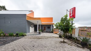 A modern house with a paved driveway, a small garden, and a signboard. - Hotel O Bromo Hill (Sukapura)