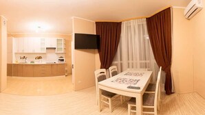 A compact living space with a dining area, kitchen, and a TV mounted on the wall. - Apart Kiev Kopernika 3-2 (Kyiv)