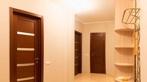 A hallway with two wooden doors, a bench, and a metal shelf unit. - Apart Kiev Kopernika 3-2 (Kyiv)