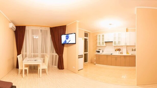 A compact living space with a dining area, a kitchen, and a TV. - Apart Kiev Kopernika 3-2 (Kyiv)