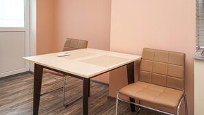 Une pièce comprenant une table et deux chaises, une fenêtre et un mur muni d’un luminaire.