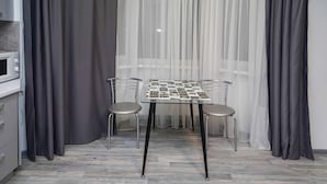 Uma pequena área de refeições com uma mesa e duas cadeiras, um micro-ondas e um armário.