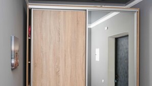 Quarto com guarda-roupa de madeira, espelho e porta que dá para outro espaço.