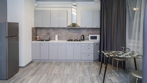 Cozinha moderna com armários cinza, uma geladeira de aço inoxidável, um micro-ondas e um fogão a gás.