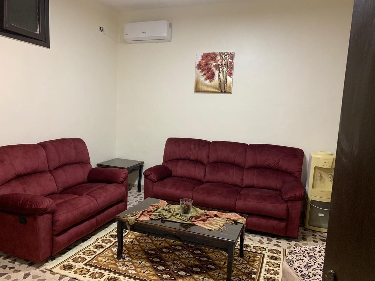 A living room with two red sofas, a coffee table, and a patterned rug.