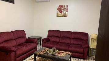 A living room with two red sofas, a coffee table, and a patterned rug.
