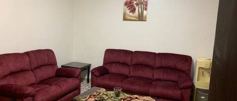 A living room with two red sofas, a coffee table, and a patterned rug.