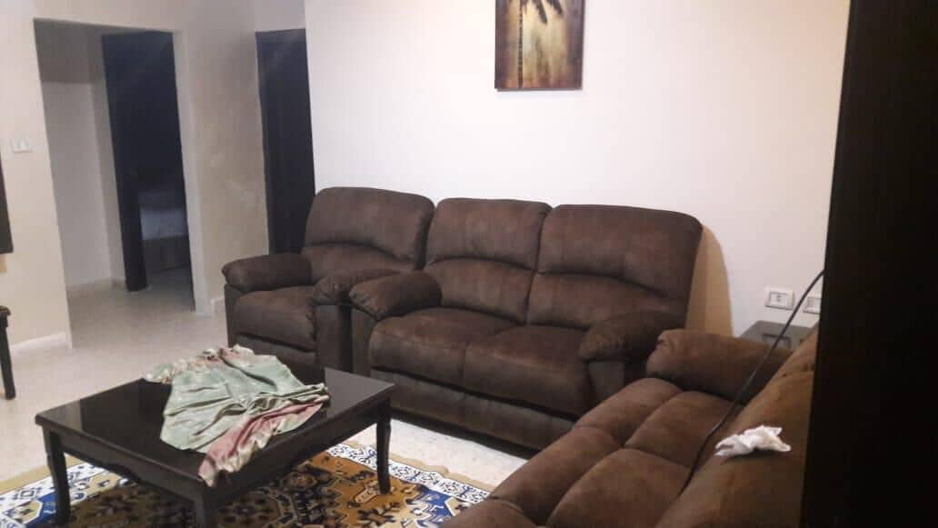 A living room with a brown sofa, a coffee table, and a painting on the wall.