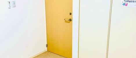 A room with a wooden door, a white wall, and a carpeted floor.