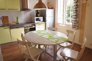 Une cuisine compacte comprenant une table à manger, des chaises, un four à micro-ondes et une cuisinière.