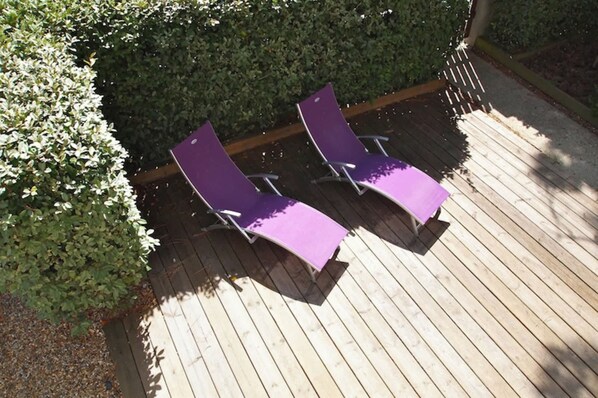 Deux fauteuils violets sont posés sur une terrasse en bois.